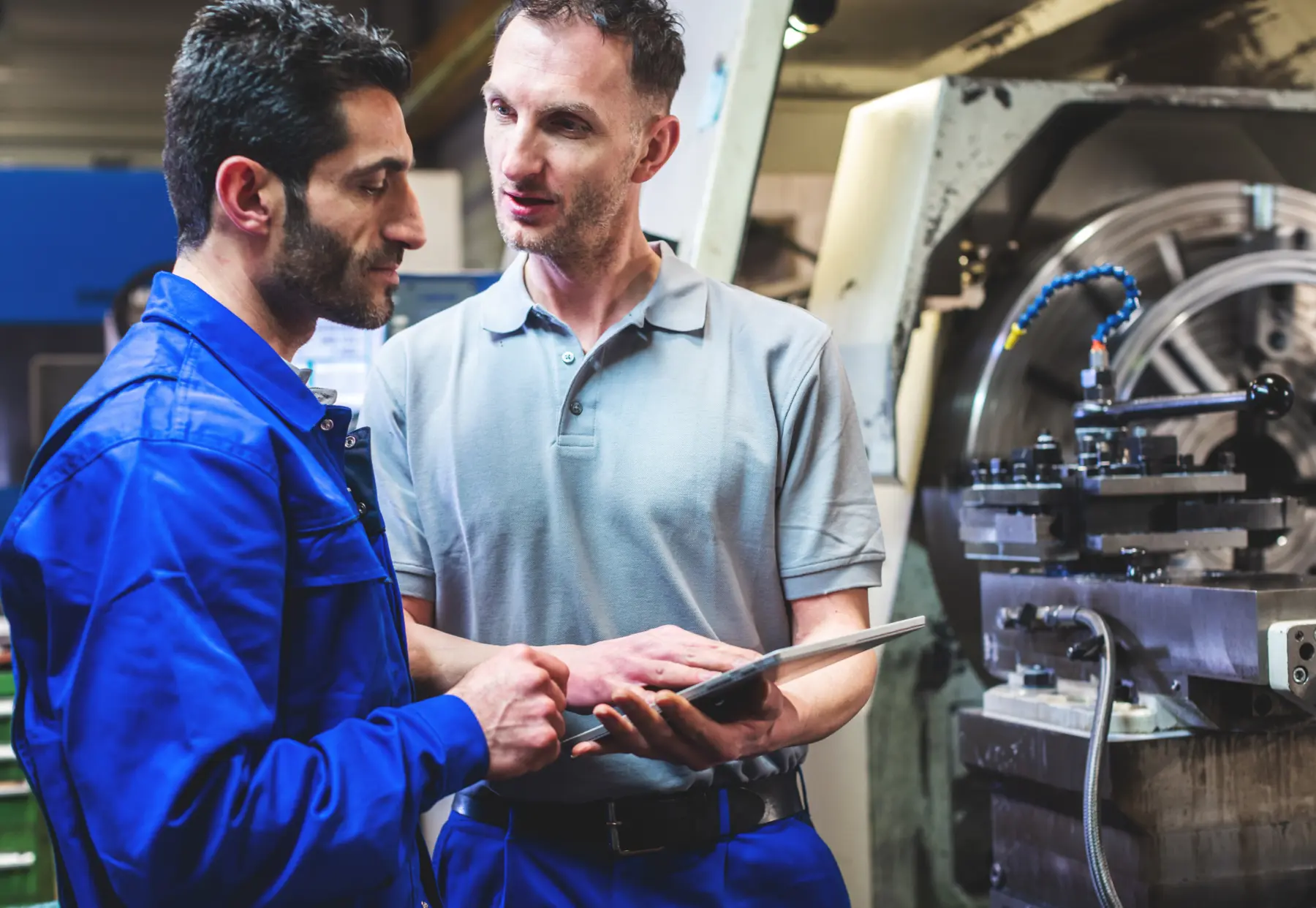 Two people reviewing work at an industrial machine